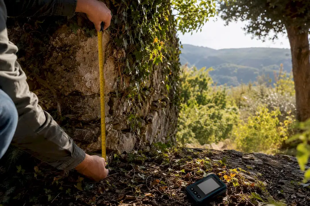 Surveyor measuring stone wall of rural property